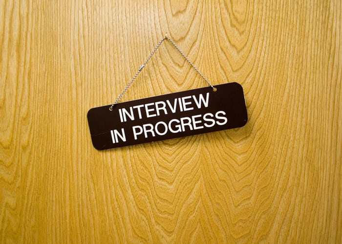 a door with a hanging sign that says "interview in progress."