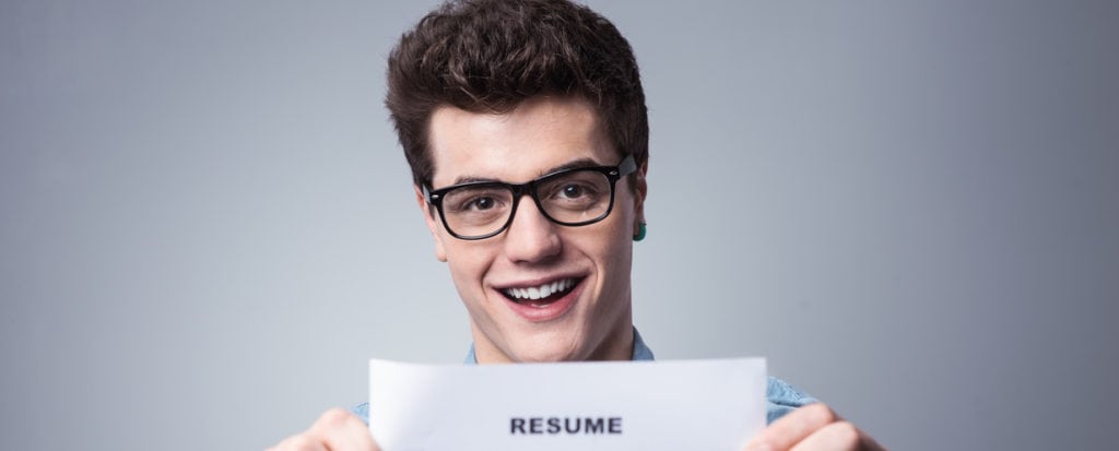 young man smiling holding resume