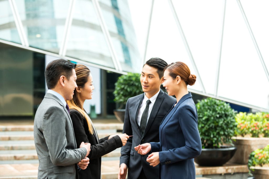 group of male and female working professionals in business attire chatting together