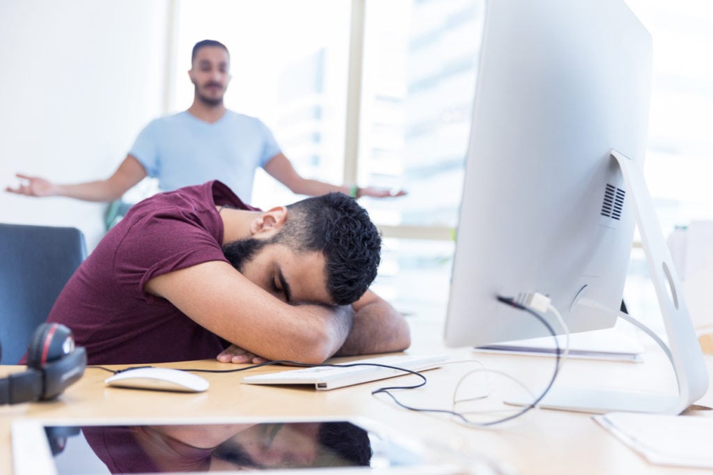 Exhausted employee sleeping on his desk after hiring