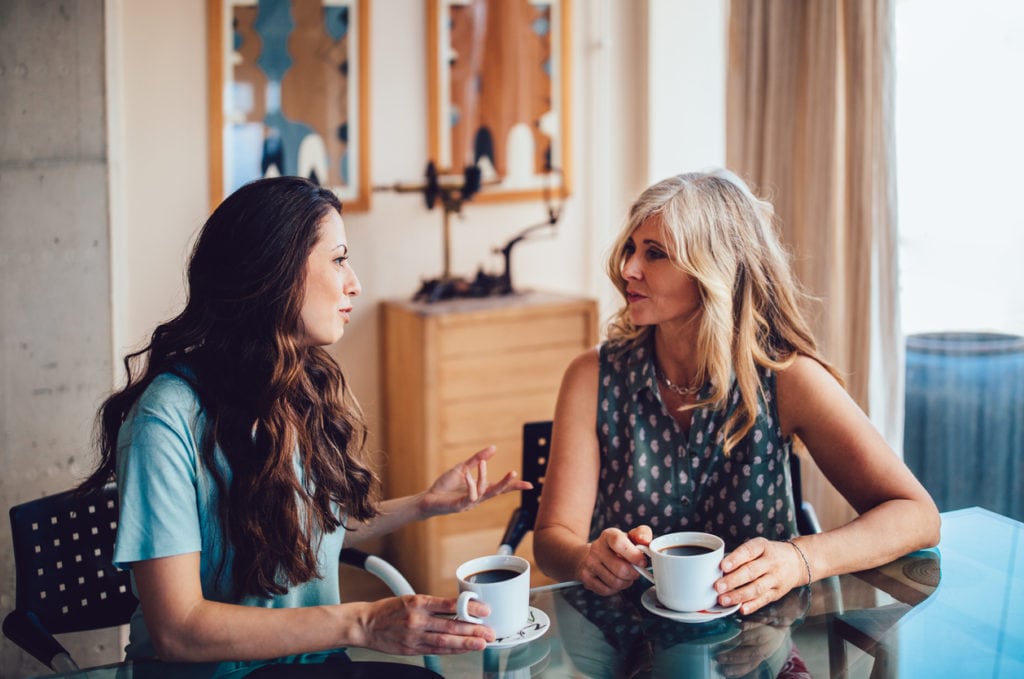 Two women discussing something at the table with coffee