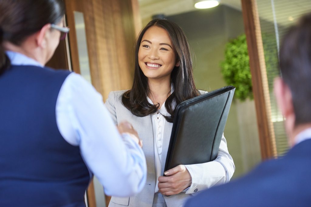 woman smiling at job interview and shaking hands during the holidays